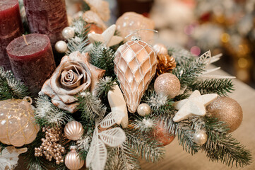 close-up of snow-covered spruce branch decorated with rose and different golden christmas tree toys