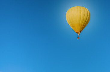 A lone balloon rises high in the blue sky