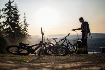 Mountain biker washing the mountain bikes in the sunset after a day of riding