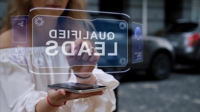 Unrecognizable blonde woman standing on the street interacts HUD hologram with text Qualified leads. Girl in white clothes uses technology of the future mobile screen