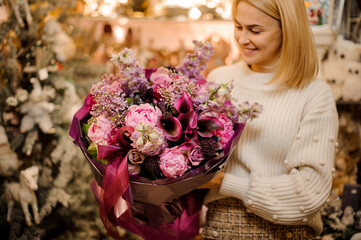 young woman florist holds great luxury bouquet of different fresh flowers.