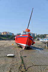 Red boat on the beach in Tenby harbour at low tide - 392476308