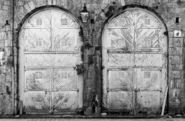 Black and White image of two old doors with peeling paint - 392476335