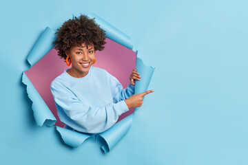 Studio shot of pleasant looking young African American woman smiles pleasantly has happy expression...