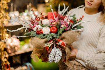 close-up of beautiful bright christmas arrangement decorated with candles in hands of woman