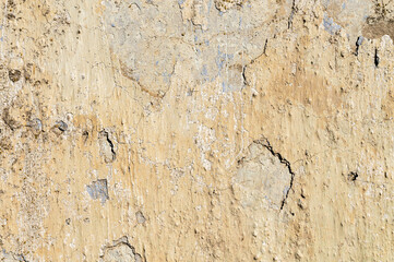 Aging cement walls with yellow blue white paint peeling off coatings outdoors on a shabby background. Vintage