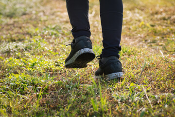 Senior woman jogger jogging in the morning in nature trail, close-up shot on legs and dirty shoes.