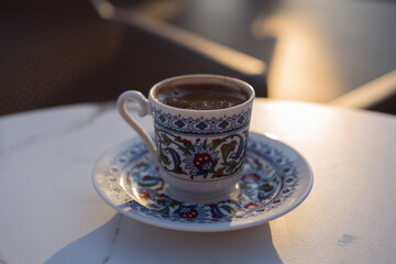 Turkish coffee in a cup with national ornament on a table on the street in a cafe. Sunset sun. High quality photo