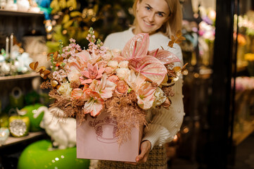 large box with gorgeous bouquet of different pink flowers in the hands of smiling woman