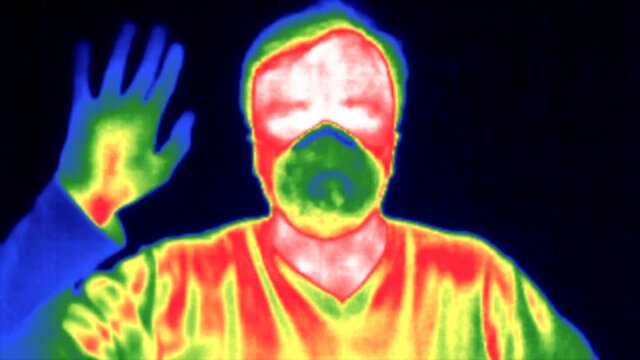 man in ffp3 protective mask gesture hello Thermal imaging camera detecting elevated body heat Covid pandemic Thermography concept.