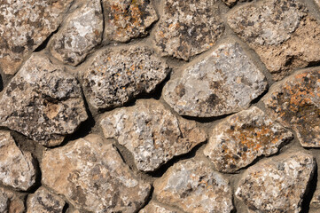 An uneven wall of decorative stacked cobblestones. Medieval background decorative insert