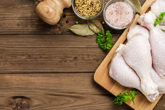 Poultry, raw chicken legs on wooden background. Top view, flat lay, space for text.