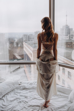 Morning of the bride. Girl in a negligee. Glamorous photo session by the window.