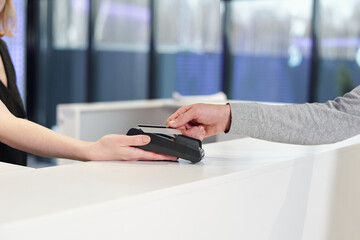 Young man holding smartphone over teminal held by female administrator