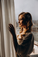 Morning of the bride. Girl in a negligee. Glamorous photo session by the window.