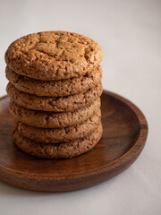 Oatmeal cookies in a wooden plate on a white background in the morning light close up