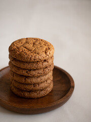 Oatmeal cookies in a wooden plate on a white background in the morning light close up