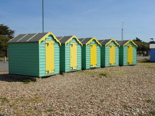 Five green and yellow sheds by the sea