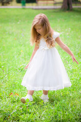 Obraz na płótnie Canvas Little girl on the lawn in a white dress