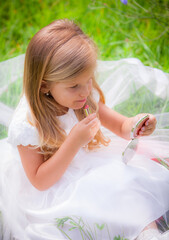 Obraz premium Little girl on the lawn in a white dress