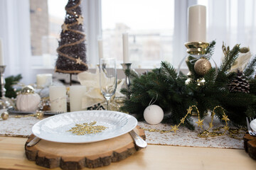New year table decor. Christmas table with candles, plates and decorations.
