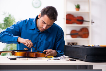Young male repairman repairing violin