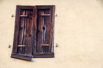 Window with old closed shutters in bright house wall. Copy Space for characters or letters.