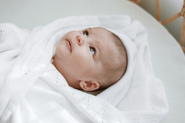 Fototapeta na wymiar Adorable baby in a white sunny bedroom. Newborn baby is resting in bed. Family morning at home.