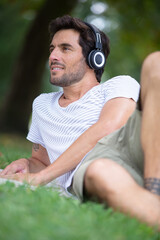 Naklejka na ściany i meble man resting in park and listening to music