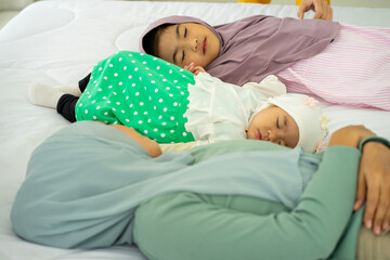 Asian Muslim young attractive businesswoman mother wearing green HIJAB headscarf work from home and caring baby girls. new normal concept. 