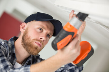 a young worker drilling ceiling