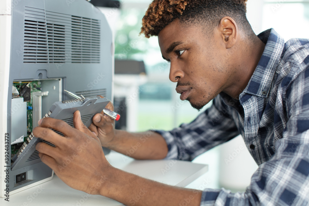 Wall mural young man repairing photocopier using screwdriver