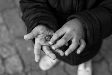 Closeup of hands of metis child playing with a little rock