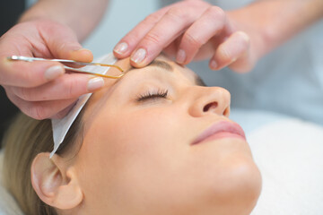 Obraz na płótnie Canvas beautician doing eyebrows of a woman in cosmetic studio