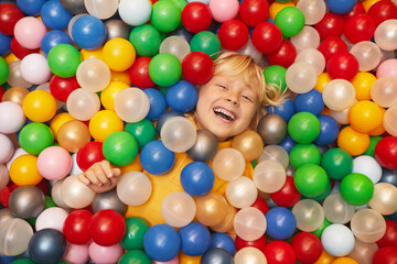 Fototapeta na wymiar High angle view of happy little boy playing with colored balls