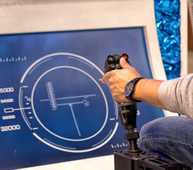 a man's hand holds a joystick in front of a flight simulator screen
