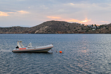 Fototapeta na wymiar A boat moored in the bay during evening on Ios Island. Cyclades, Greece