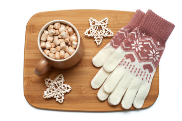 Mug with hot chocolate and marshmallows, warm gloves on a wooden tray