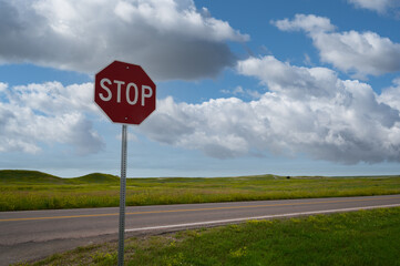 Stop sign against blue sky with road in background