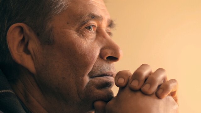 Senior man at home, looking up, praying prayer, thinking. Portrait, closeup.