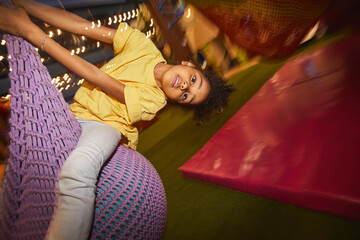 Fototapeta na wymiar Playful African little girl having fun in the entertainment park she swinging