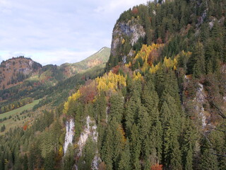 Herbst in den Alpen mit bunt gefärbten Bäumen und Wäldern an den Berghängen