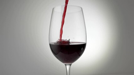Slow motion cinemagraph of red wine being poured into glass