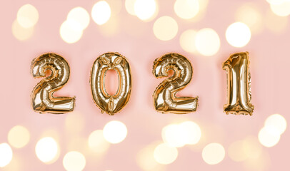 Golden foil balloons made numbers 2021 on pink background with light bokehs. Happy new year celebration party. Greetings and congratulation concept.