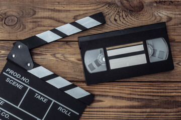 Movie clapper board and video cassette on wooden background. Cinema industry, entertainment. Top...
