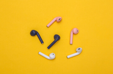 Different colors Wireless headphones on yellow background. Top view. Minimalism