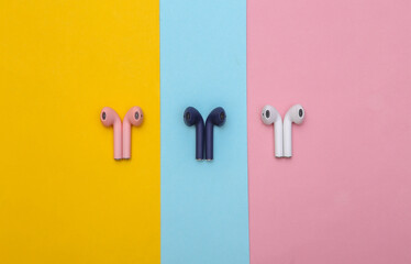 Different colors Wireless headphones on colorful pastel background. Top view. Minimalism