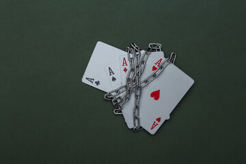 Obraz premium Four aces wrapped in a steel chain on green background. Prohibition of gambling business, casinos