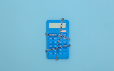 Calculator wrapped in steel chain on a yellow background. Top view