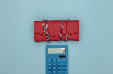 Leather wallet wrapped in a steel chain and calculator on blue background. Top view